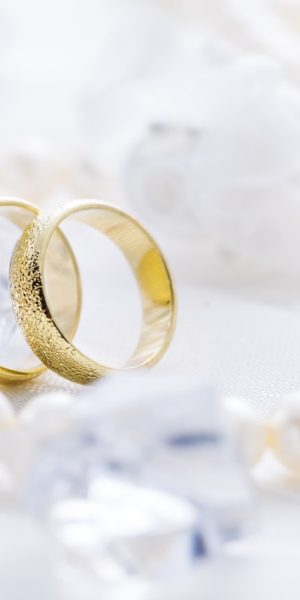 Two golden rings with pearl necklace and on white background as symbol of love and marriage